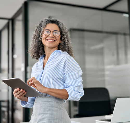 smiling woman in striped blouse holding tablet in modern office smiling employee using technology for work