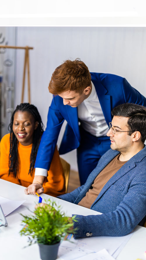 three professionals collaborating in a meeting with documents and a plant on the table