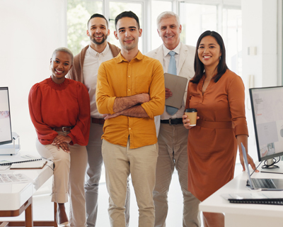 diverse team of professionals posing together in a modern office environment standing confidently with computers displaying work two colleagues smiling