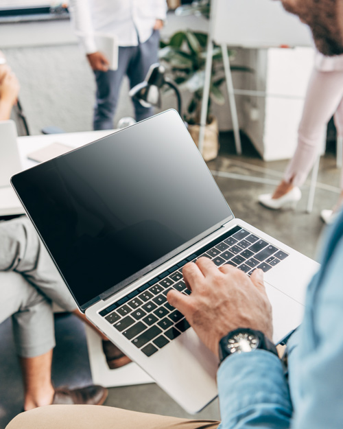 person using a laptop in a meeting room with two people in the background showcasing teamwork and collaboration