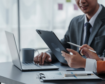 business professionals discussing project details with tablet and laptop on desk