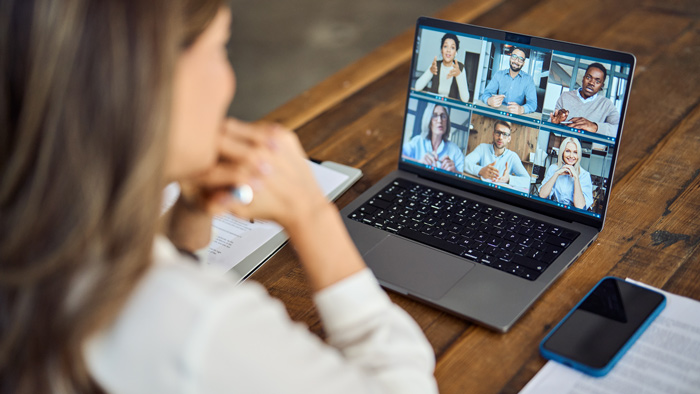 woman participating in virtual meeting on laptop with six people displayed on screen discussing various topics 7 important insights and strategies